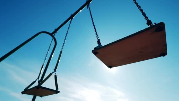 Empty swings are swaying against the sunlight. Empty swings, covid-19 concept. — Stock Video