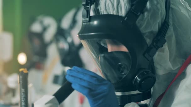 방직 마스크를 쓴 연구가 들은 현미경을 조사하고 있다 — 비디오