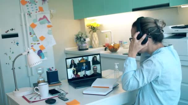 A worker in headset talks to people via laptop while staying home during pandemic. Zoom, videocall , video conference, online meeting, working remotely concept. — Stock Video