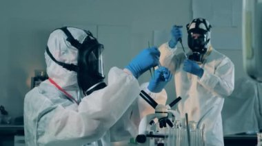 Kimyagerler, koronavirüs salgını sırasında tehlikeli madde kıyafetlerinin test tüpleriyle çalıştığını söylüyorlar..
