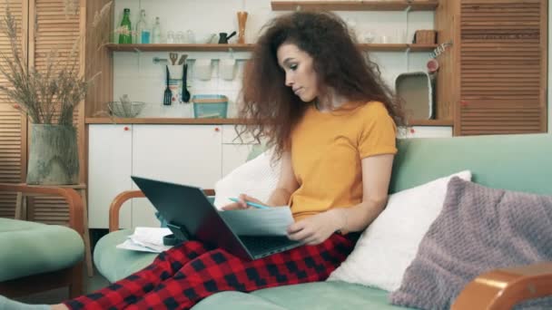 Concetto di apprendimento remoto. Una ragazza lavora sul computer portatile, seduta su un divano . — Video Stock