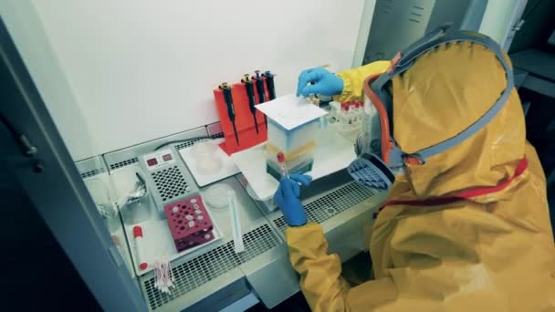 Onderzoeker in een hazmat pak werkt met stoffen — Stockvideo