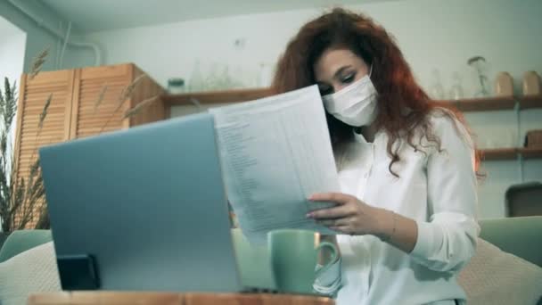 Zakenvrouw in masker werkt vanuit huis met documenten tijdens quarantaine. — Stockvideo