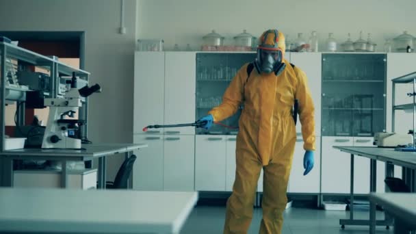 Az egészségügyi ellenőr vegyi anyagokat porlaszt a laborban. — Stock videók