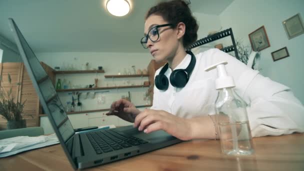 Un lavoratore utilizza disinfettante per le mani mentre lavora sul computer portatile a casa . — Video Stock