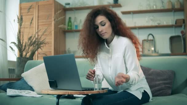 Een meisje reinigt haar handen tijdens het werken op laptop tijdens quarantaine. Afstandswerkconcept. — Stockvideo
