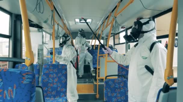 Lidé v ochranných oblecích zabíjejí virus v autobuse během dezinfekce. — Stock video