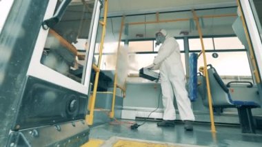 Coronavirus salgını sırasında belediye otobüsünü dezenfekte eden kişi.