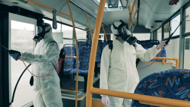 İki işçi bir otobüsü temizliyor, koronavirüsten dezenfekte ediyorlar.. — Stok video