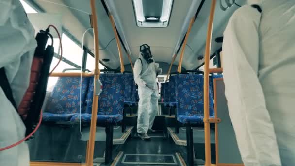 Desinfectiewerkers reinigen een bus met sproeiapparaat tijdens een pandemie. — Stockvideo