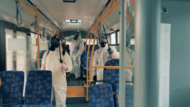 Männer in Schutzanzügen desinfizieren Stadtbus, um Virus zu töten. — Stockvideo