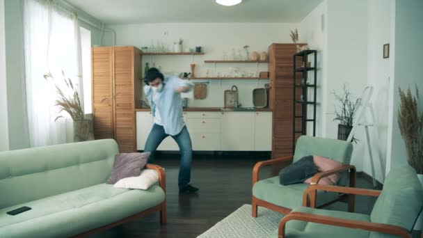 Ein erwachsener Mann mit Gesichtsmaske tanzt in seiner Wohnung. COVID-19 Lockdown-Konzept. — Stockvideo