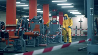 Dezenfeksiyon işçisi boş bir spor salonunu temizliyor.