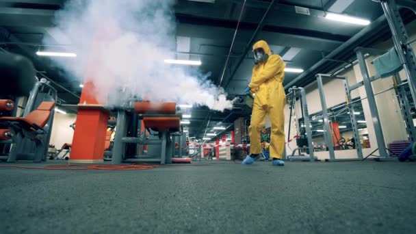 Sanitární pracovník kouří chemikálie v tělocvičně — Stock video