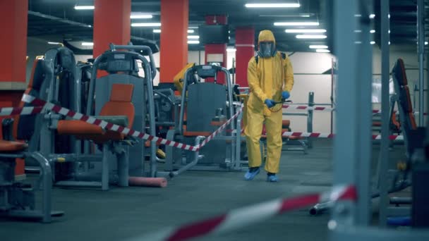 Gym wordt gedesinfecteerd door een sanitair werker — Stockvideo