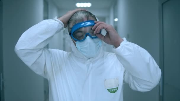 Clinic worker takes off goggles and mask while working in hospital. — Stock Video