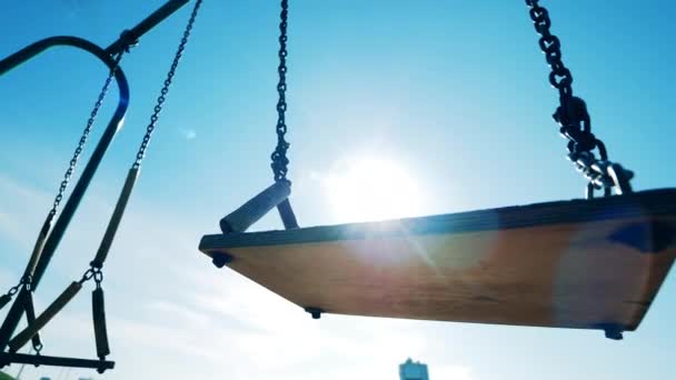 Close up of swings seat moving in sunlight. Empty swing, covid-19 concept. — Stock Video