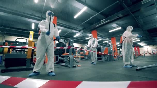 Sanitetsarbetare pulveriserar kemikalier i gymmet — Stockvideo