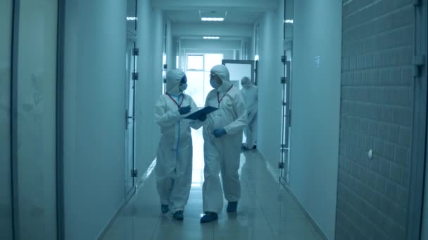 La gente camina en el hospital, usando trajes de protección durante la pandemia . — Vídeo de stock