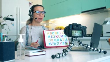 Çevrimiçi çalışma, evden çalışma, uzaktan öğrenme. Karantina sırasında, covid-19 salgını. Neşeli öğretmen kendini eğitici bir videoda çekiyor.
