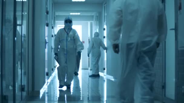 Doctors in hazmats walk in hallway during working day. — Stock Video