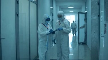 İnsanlar klinikte çalışıyor, salgın sırasında koruyucu elbiseler giyiyorlar..