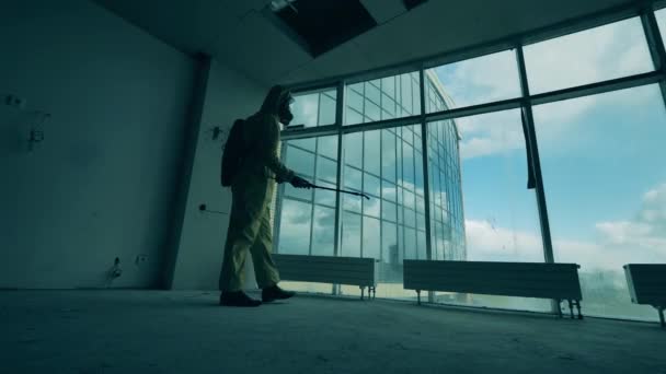 Trabajador sanitario está desinfectando ventanas panorámicas en una habitación vacía — Vídeos de Stock