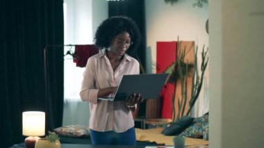 Afro-Amerikalı bir kadın online alışveriş için dizüstü bilgisayar kullanıyor. Uzaktan alışveriş, online satın alma kavramı.