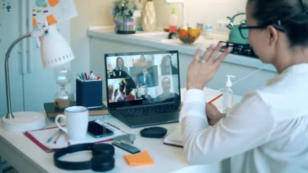 Mulher fala com seus colegas via laptop enquanto fica em casa . — Vídeo de Stock