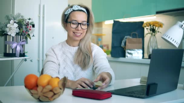 Mujer joven utiliza el ordenador portátil mientras que las compras en línea en casa . — Vídeos de Stock