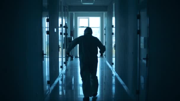 Güvenlik kıyafetli sağlık görevlisi koridorda mola veriyor. — Stok video