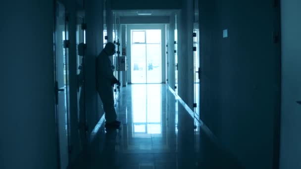 Tehlikeli madde giysisi içindeki doktor koridorda mola veriyor. — Stok video