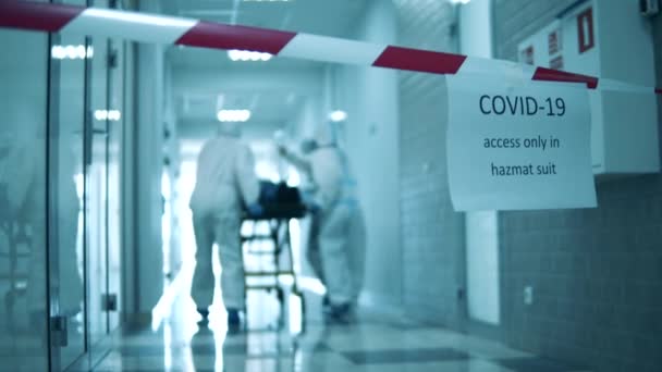 In quarantaine gehouden gang met artsen die er een patiënt langs vervoeren. Covid-19-concept. — Stockvideo