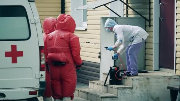 Nurse with a disinfectant and medical staff in red suits — Stock Video