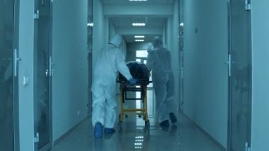 Hasta taşımacılığı, bir grup doktor tarafından güvenlik kıyafetleri içinde tutuluyor.
