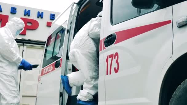 I paramedici in tuta anti-pericolo stanno entrando in ambulanza. — Video Stock