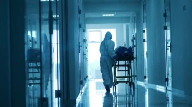 Doktor bir hastayla birlikte hastane boyunca bir tramvayı hareket ettiriyor. Coronavirus Hastanesi, COVID-19 Klinik Konsepti.