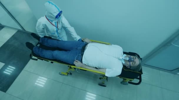 COVID-19 patient in coronavirus hospital. Top view of a male patient getting relocated on a rolling table — Stock Video