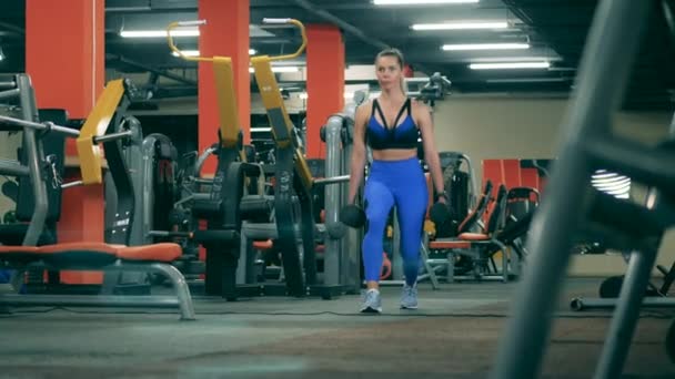 Strong woman is doing crossfit with dumbbells in the gym — Stock Video