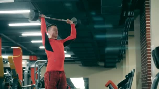 Joven está levantando un bar en el gimnasio — Vídeos de Stock