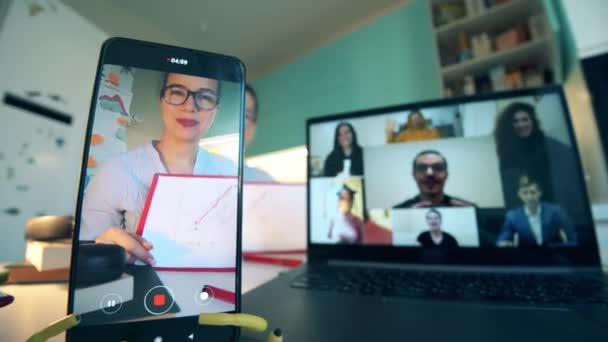 Egy okostelefon és egy laptop képernyői egy munkahelyi videohívás során. Videokonferencia-üléskoncepció. — Stock videók