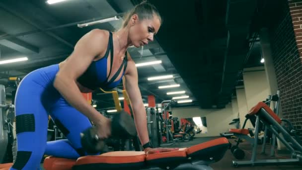 A lady is doing exercises with dumbbells in the fitness center — Stock Video