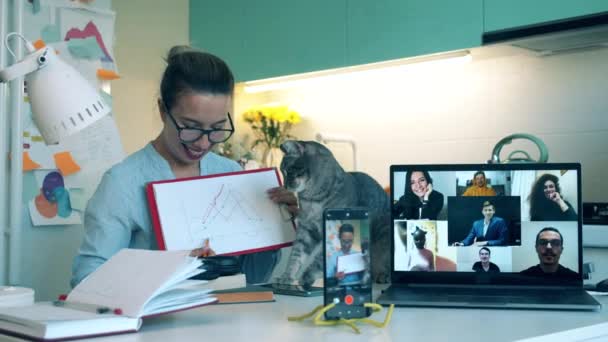 Een vrouw legt een grafiek uit aan haar collega 's tijdens een videogesprek. Bijeenkomst online, werken op afstand met behulp van videocall. — Stockvideo