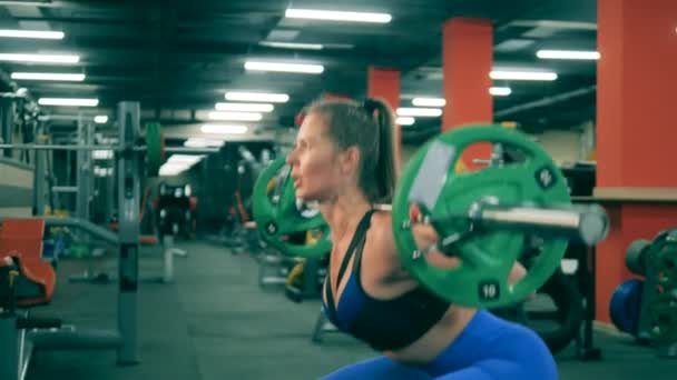 Silna kobieta podnosi poprzeczkę na siłowni. — Wideo stockowe