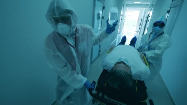 COVID-19 patient in coronavirus hospital. Doctors are transporting a patient on a medical trolley — Stock Video