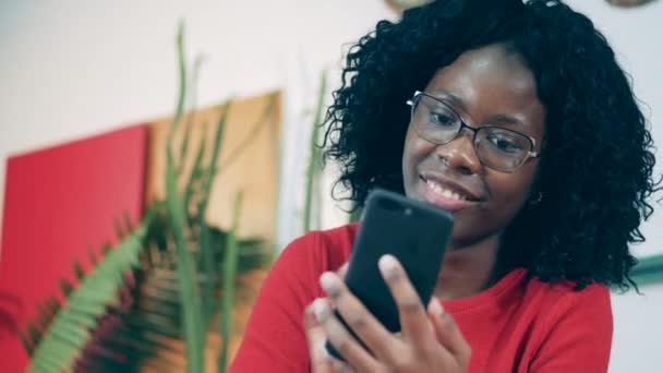 African lady is entering card data into her phone and smiling — Stock Video