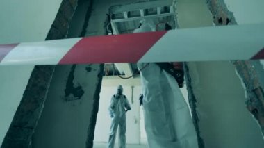 İki kişi bir odayı ilaçlama makinesiyle dezenfekte ediyor..