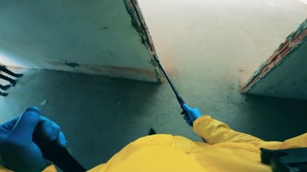 Egy munkás fertőtlenítőszerrel tisztítja meg a befejezetlen épületet.. — Stock videók