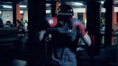 Erkek sporcu boks yaparken VR kulaklığı takıyor.