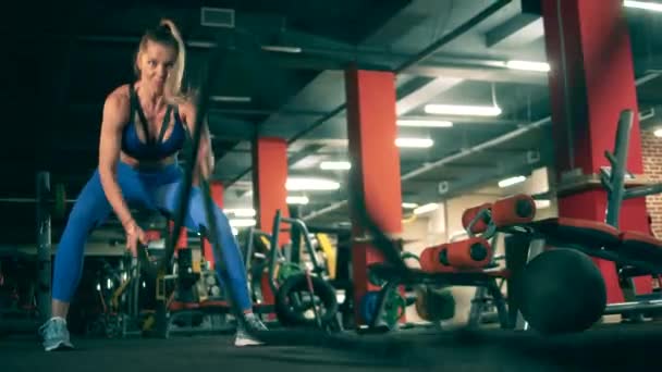 Young woman exercises with ropes in modern gym. — Stock Video